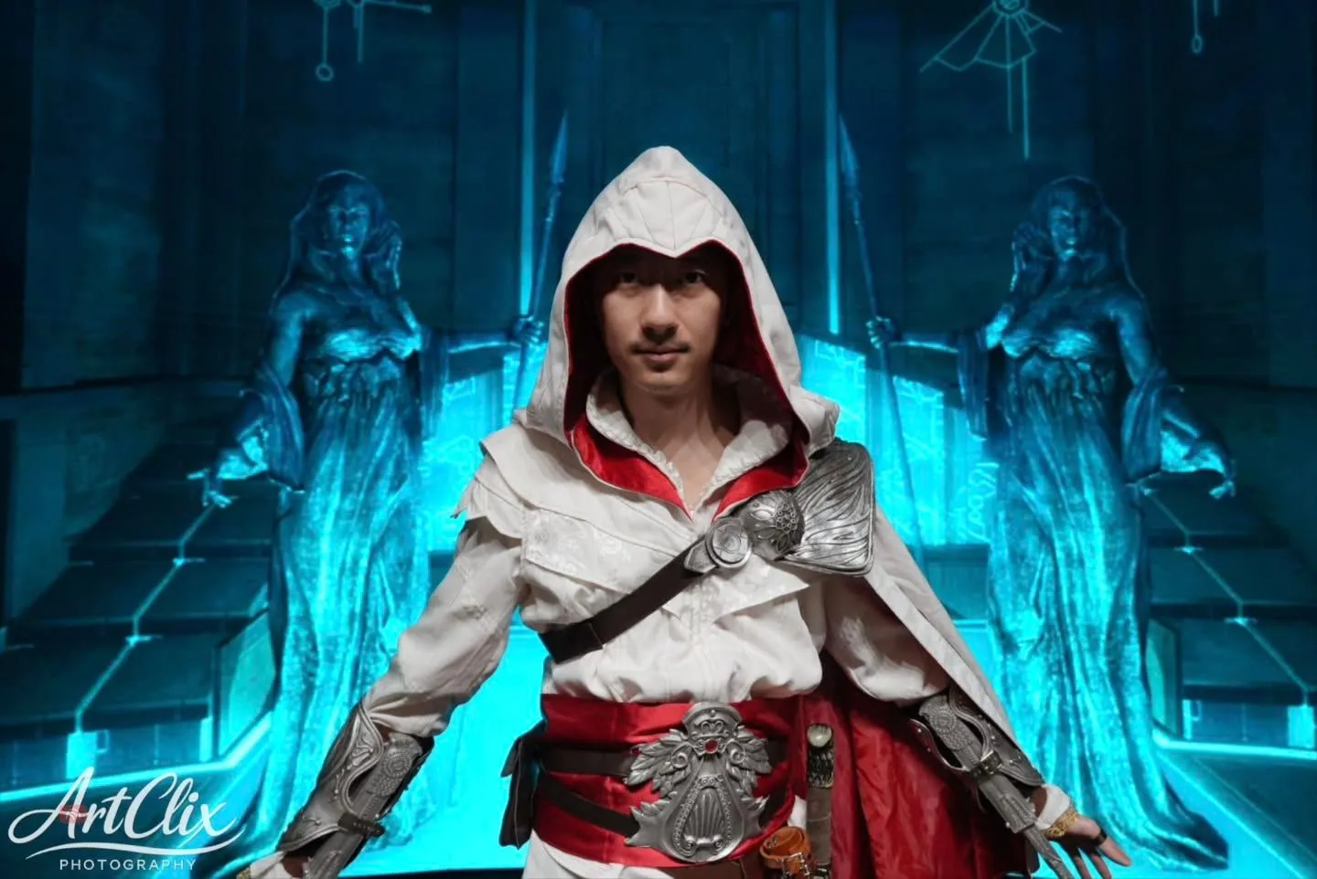 ਨੀਲੇ ਇਮਾਰਤੀ ਦ੍ਰਿਸ਼ ਅੱਗੇ ਹੁੱਡ ਵਾਲੇ Assassin’s Creed ਪਹਿਰਾਵੇ ਵਿੱਚ Spartan501