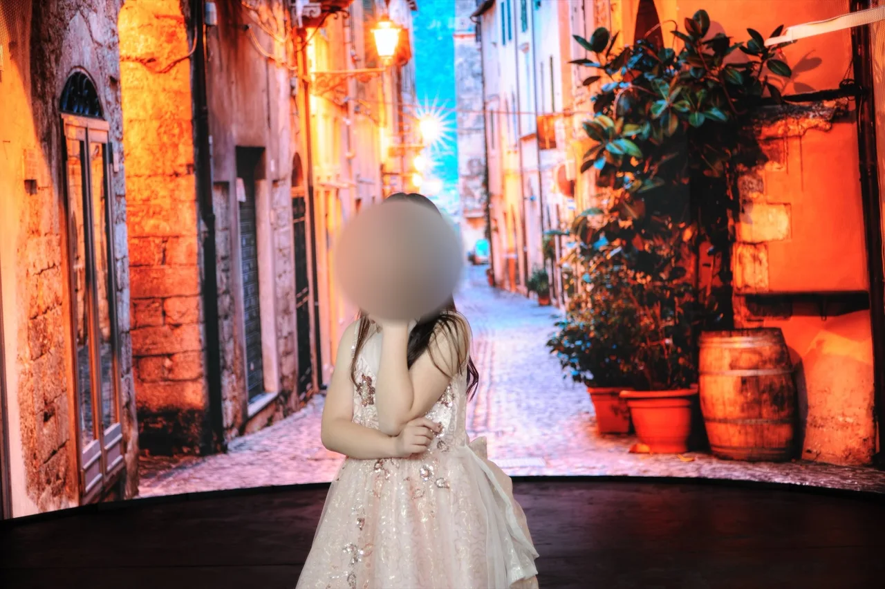 Young girl in a sequined gown posing before an Italian old-town street on the LED wall