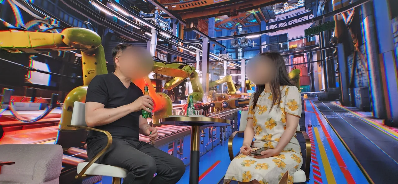 Two guests mid-interview before the robot factory LED wall