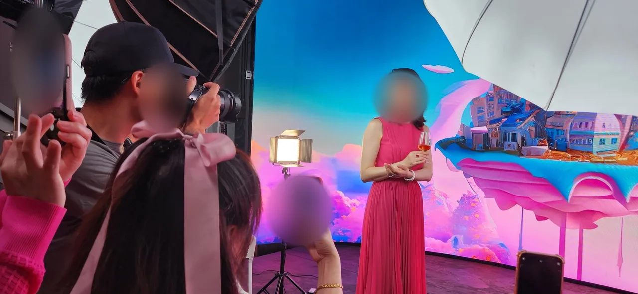 Woman in a red dress photographed before a pink candy-land LED wall, behind the scenes