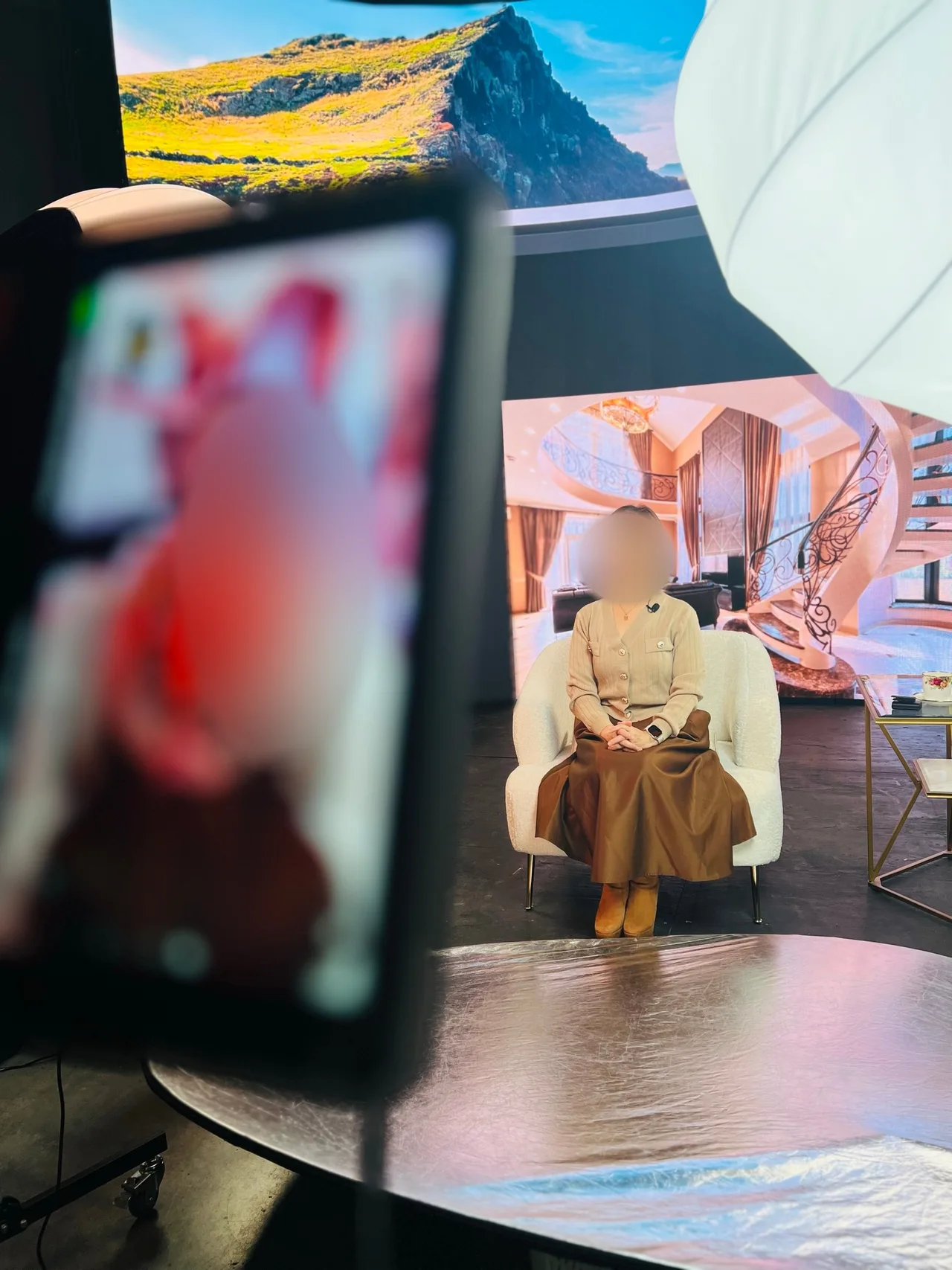 Female host seated in front of an LED wall interior backdrop during interview