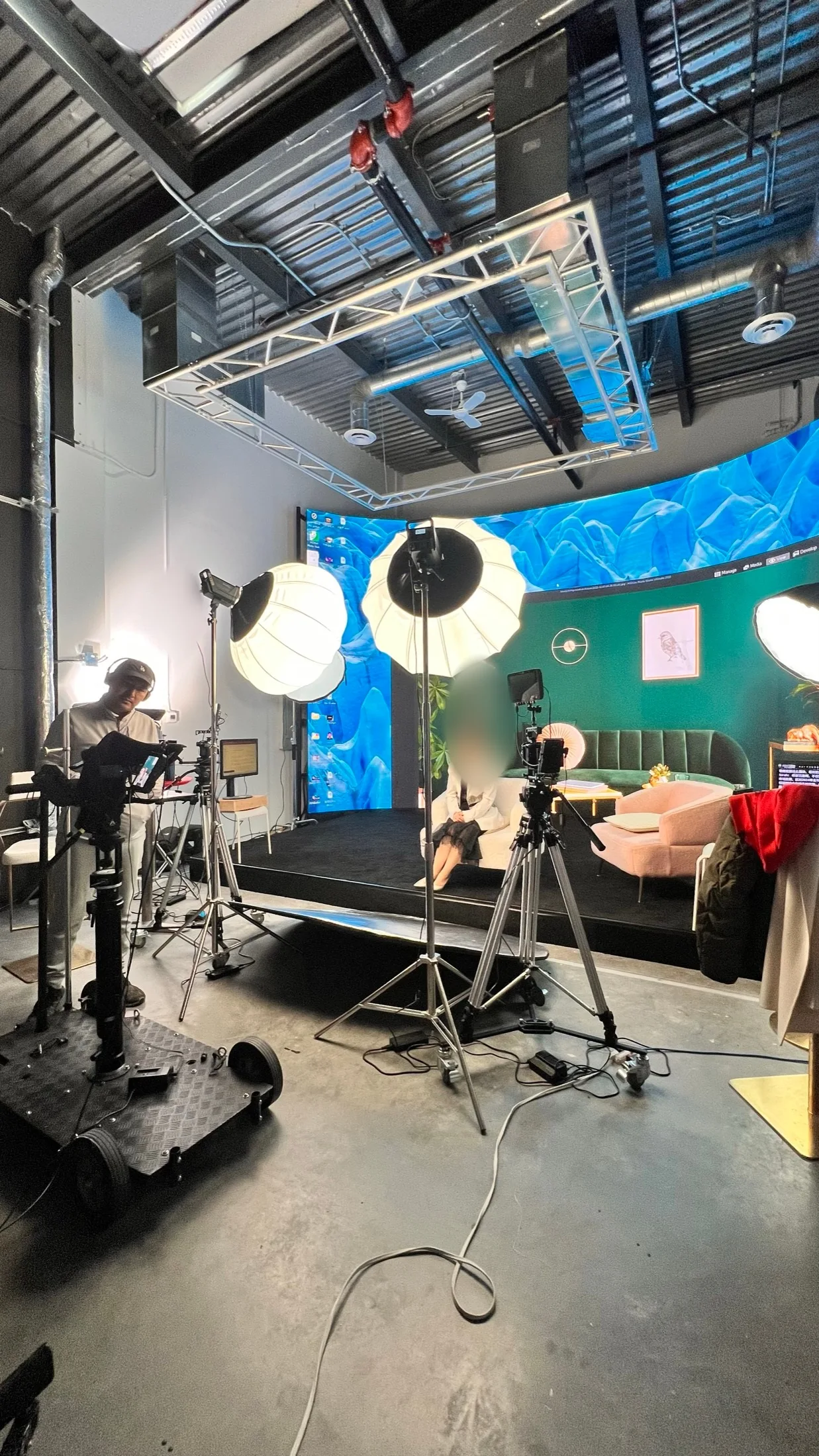 Wide shot of talk show set with green room LED backdrop and crew