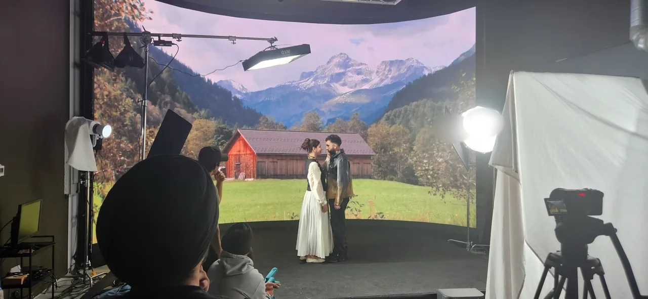 Couple performing a romantic scene in front of an alpine meadow and barn backdrop on the LED wall at Upperland Studio, Richmond BC