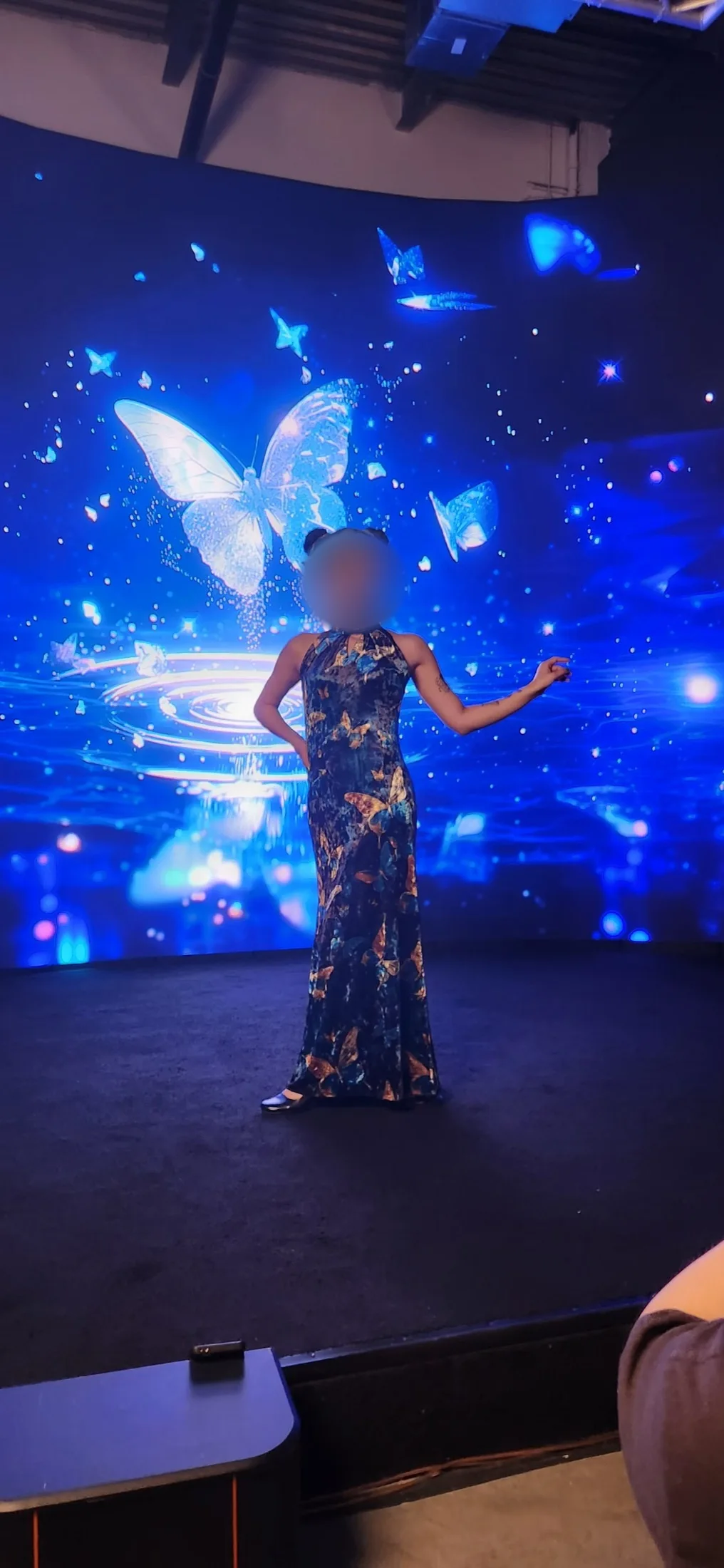 Model in a butterfly-print qipao gown posing in front of a glowing blue butterfly backdrop on the LED wall at Upperland Studio, Richmond BC