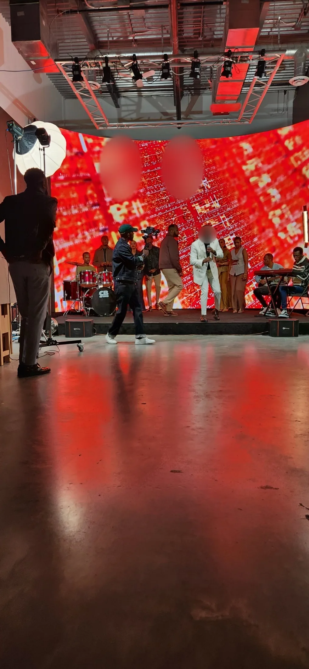 Lead singer in a white suit performing with a live band against a red city aerial backdrop on the LED wall at Upperland Studio, Richmond BC