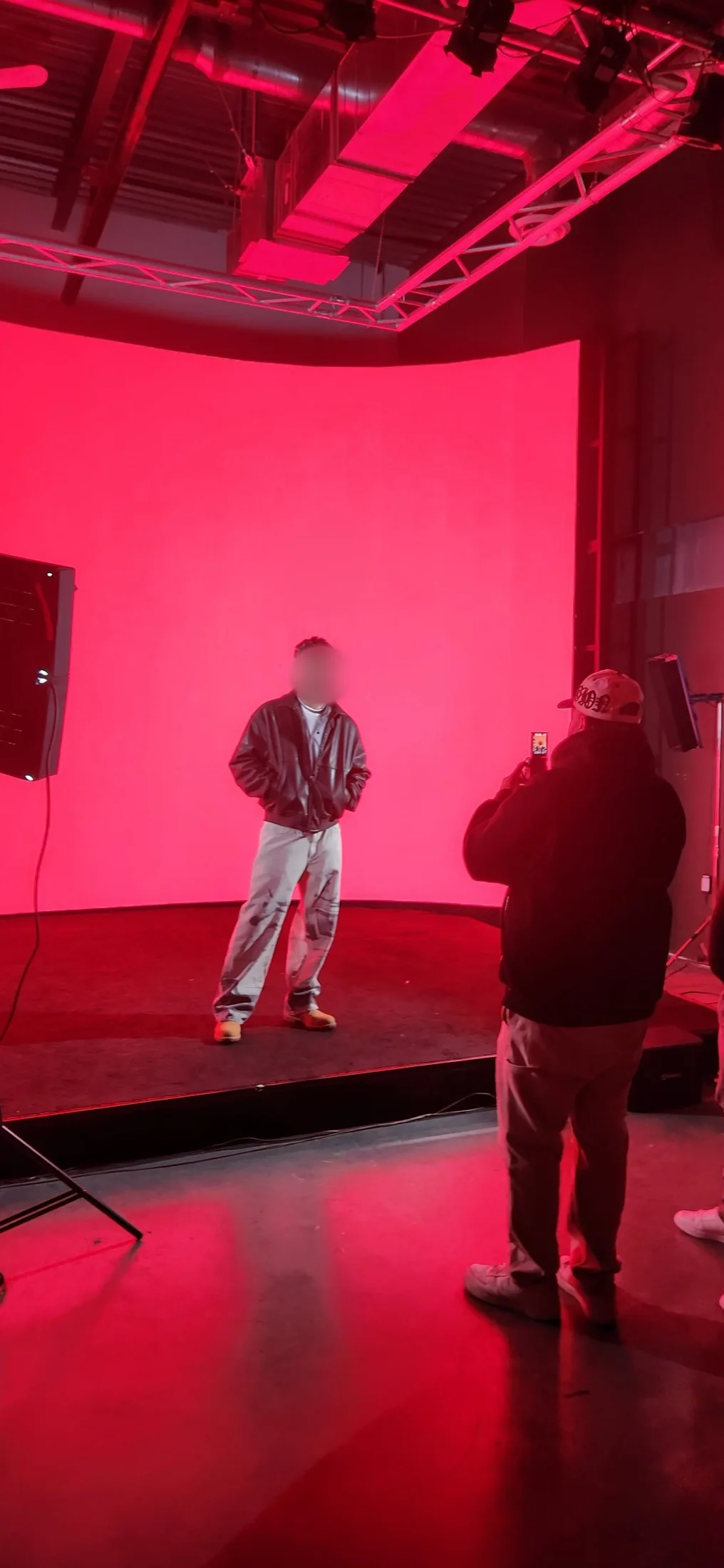 Singer in a leather jacket and sunglasses posing against a solid red LED wall during a music video shoot at Upperland Studio, Richmond BC