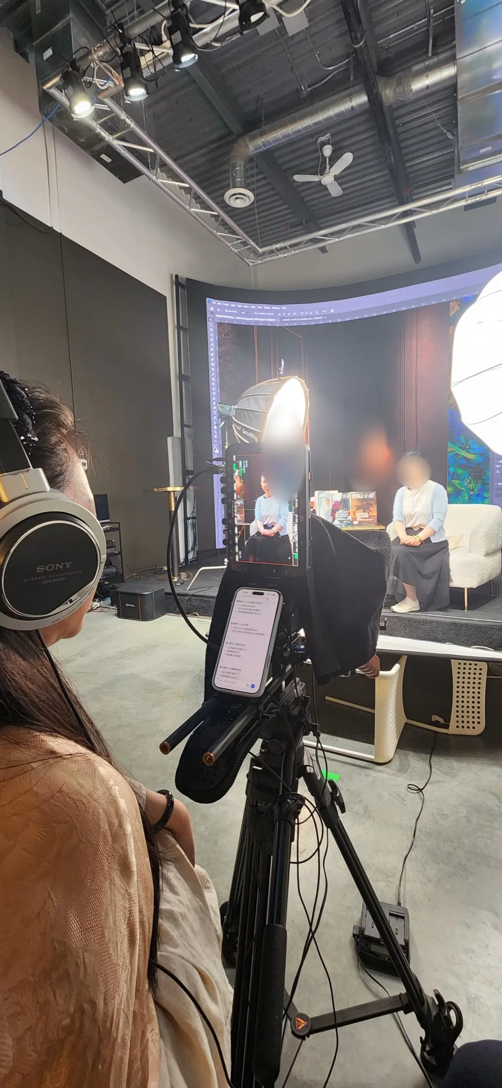 Behind-the-scenes wide shot of an interview production with lighting, camera crew and an art gallery backdrop, Upperland Studio Richmond BC