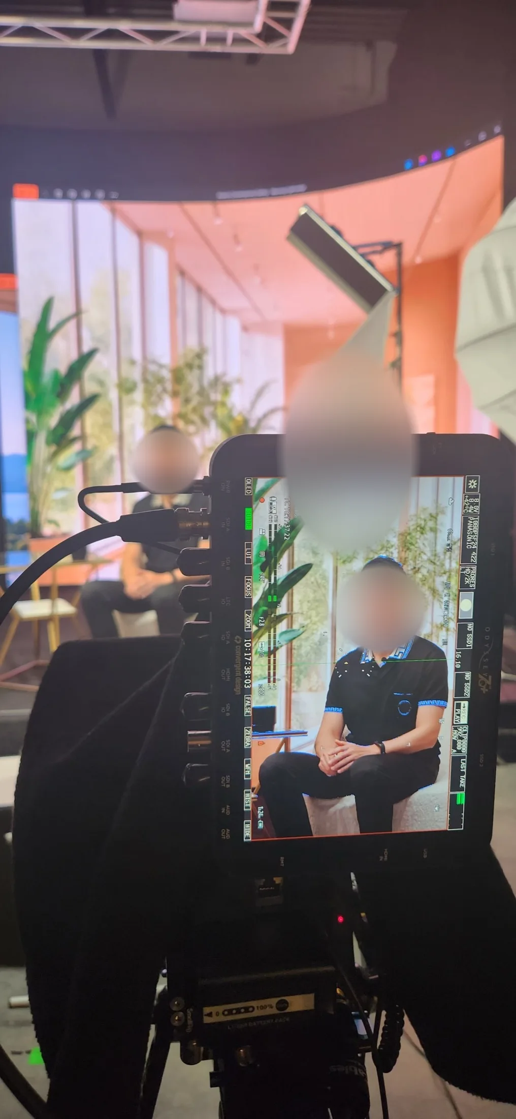 Guest speaking during an interview shoot with a bright conservatory scene on the LED wall behind him