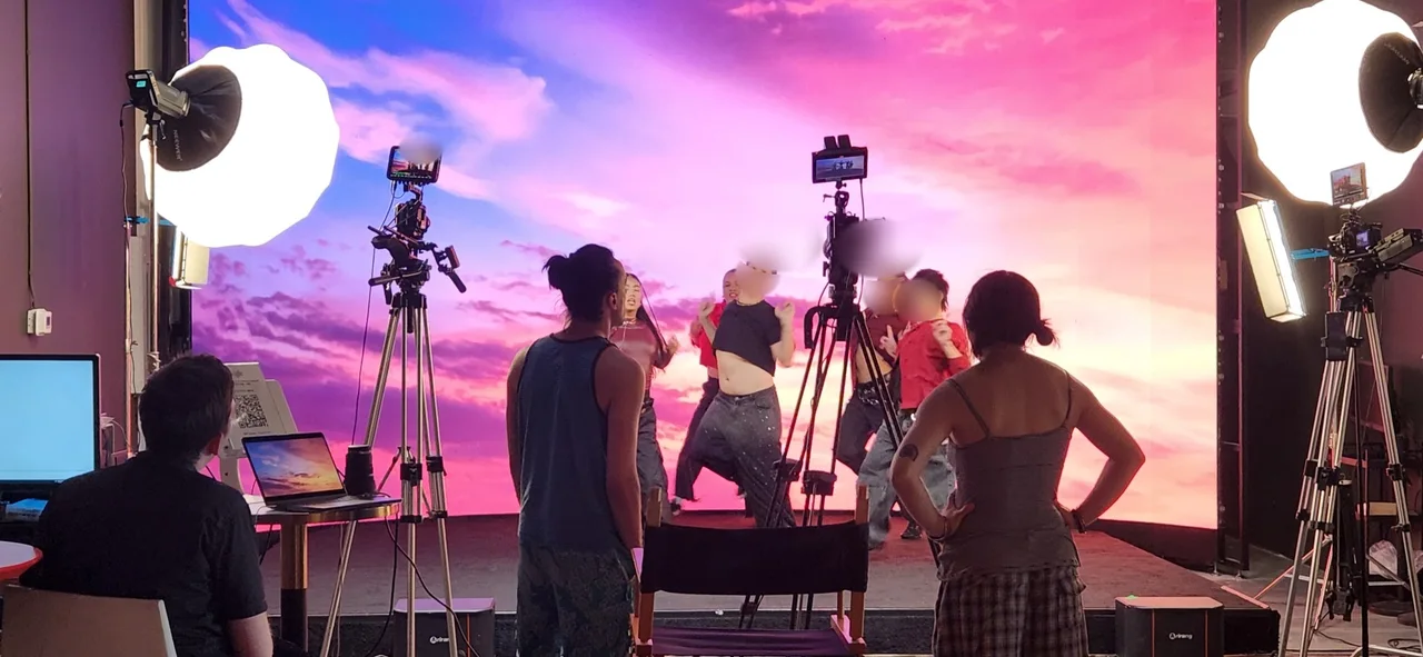 Dance crew rehearsing in front of a pink sunset LED wall while two cameras record at Upperland Studio