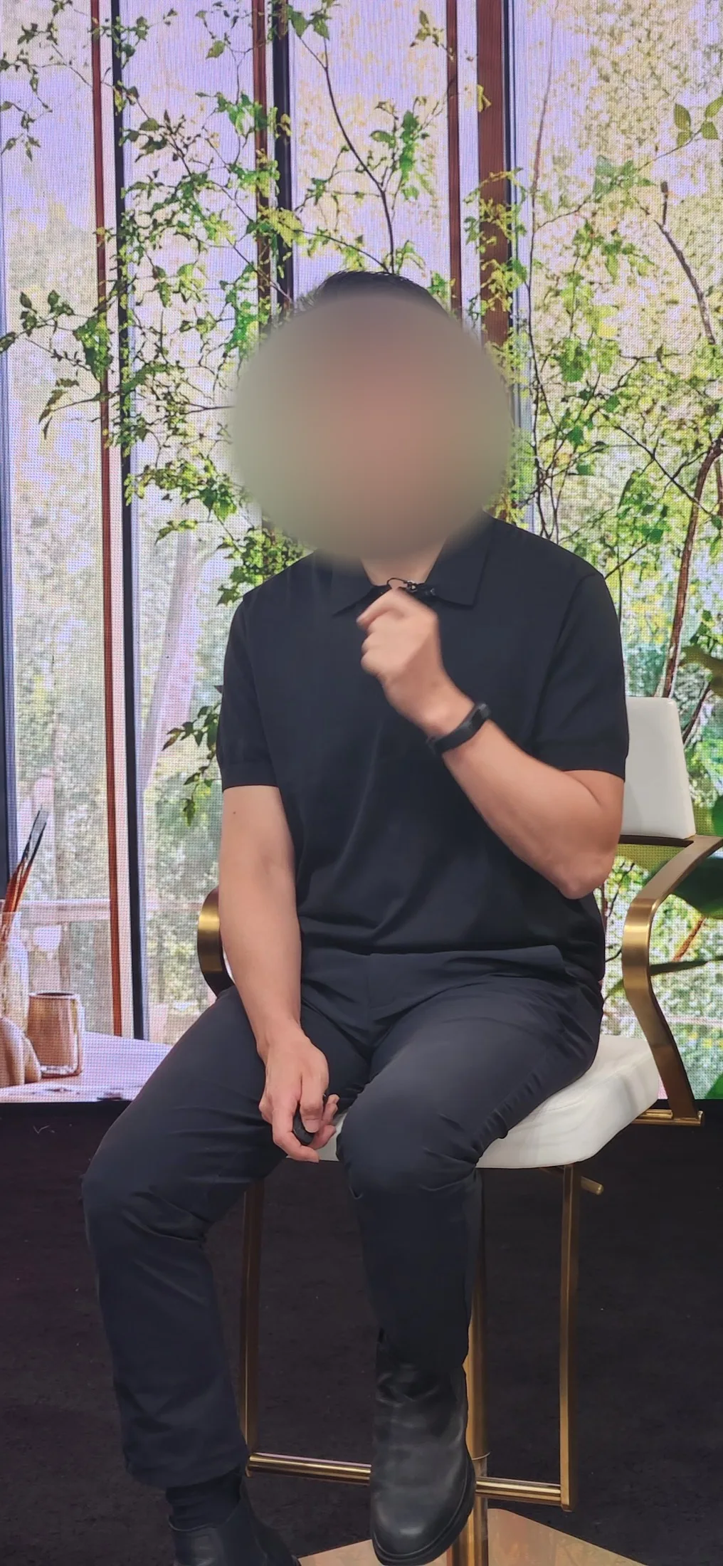 Man in a black polo shirt speaking to camera against a green foliage LED wall backdrop