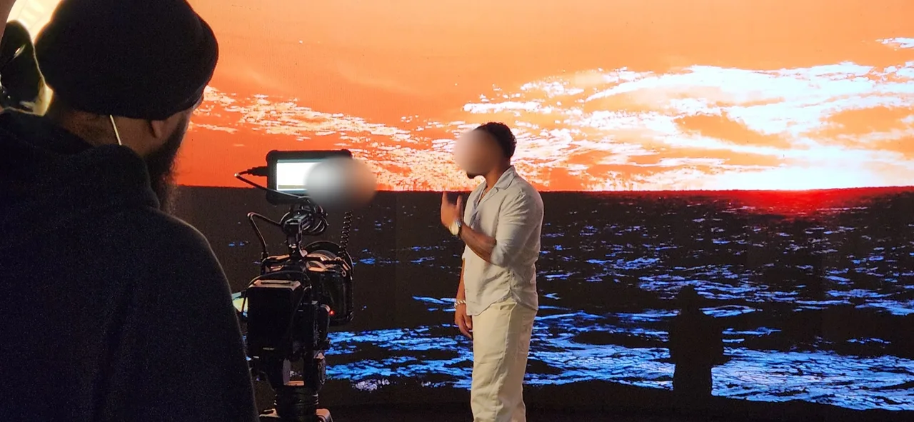 Male singer performing with a microphone in front of an ocean sunset LED wall