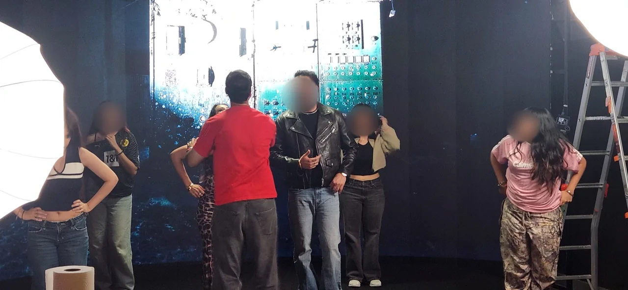 Bearded Punjabi singer in a leather jacket and sunglasses on set with dancers and crew