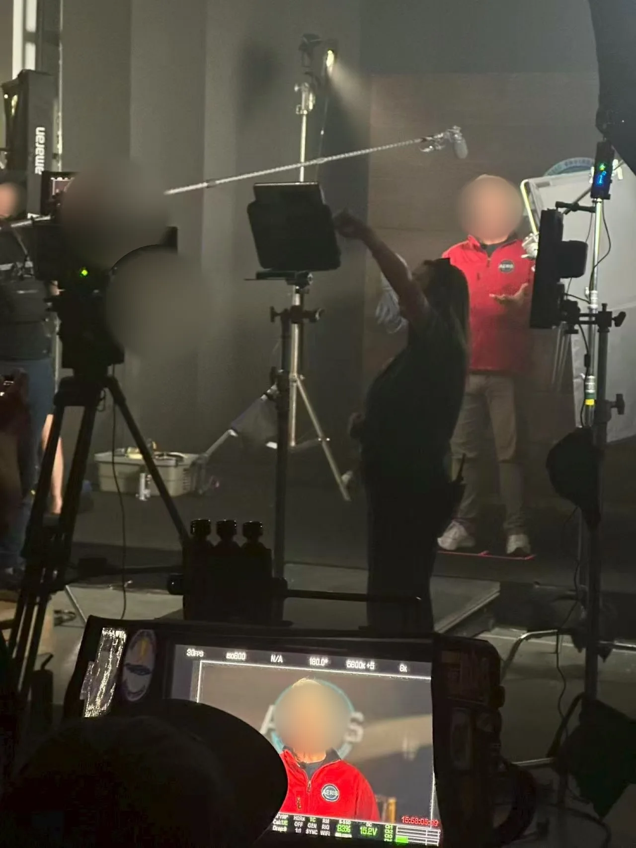 Presenter in a red AERIS jacket shown on the camera monitor, with crew and boom microphone