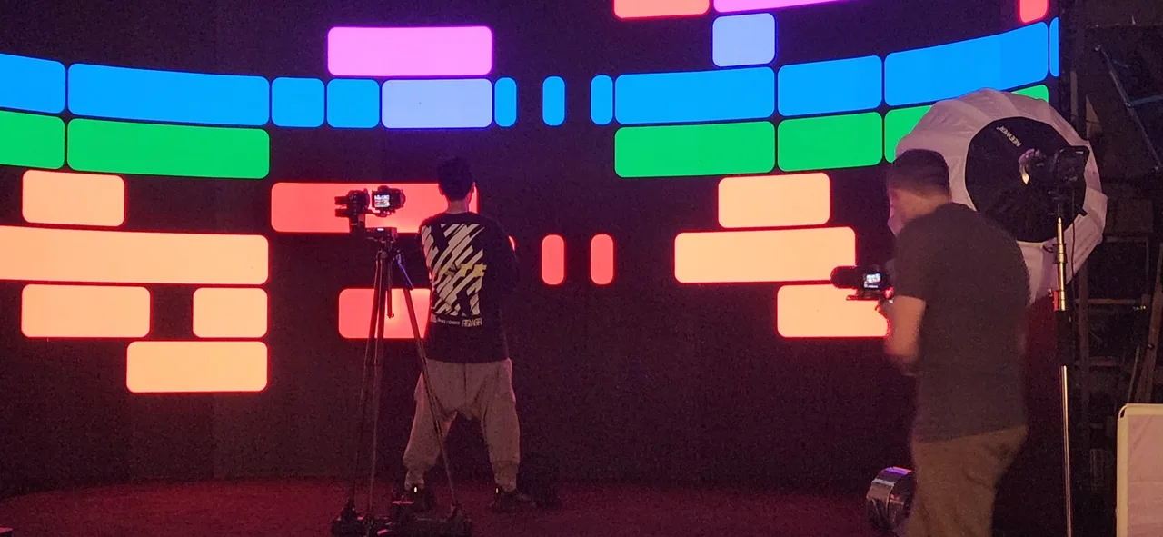 Crew filming against a colorful equalizer-block LED graphic backdrop