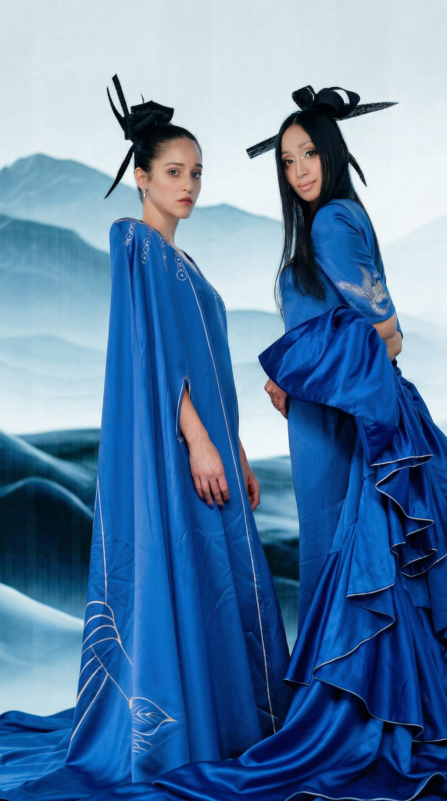 Two models in royal blue New Chinese couture gowns with cape and ruffled details, mountain LED backdrop at Upperland Studio